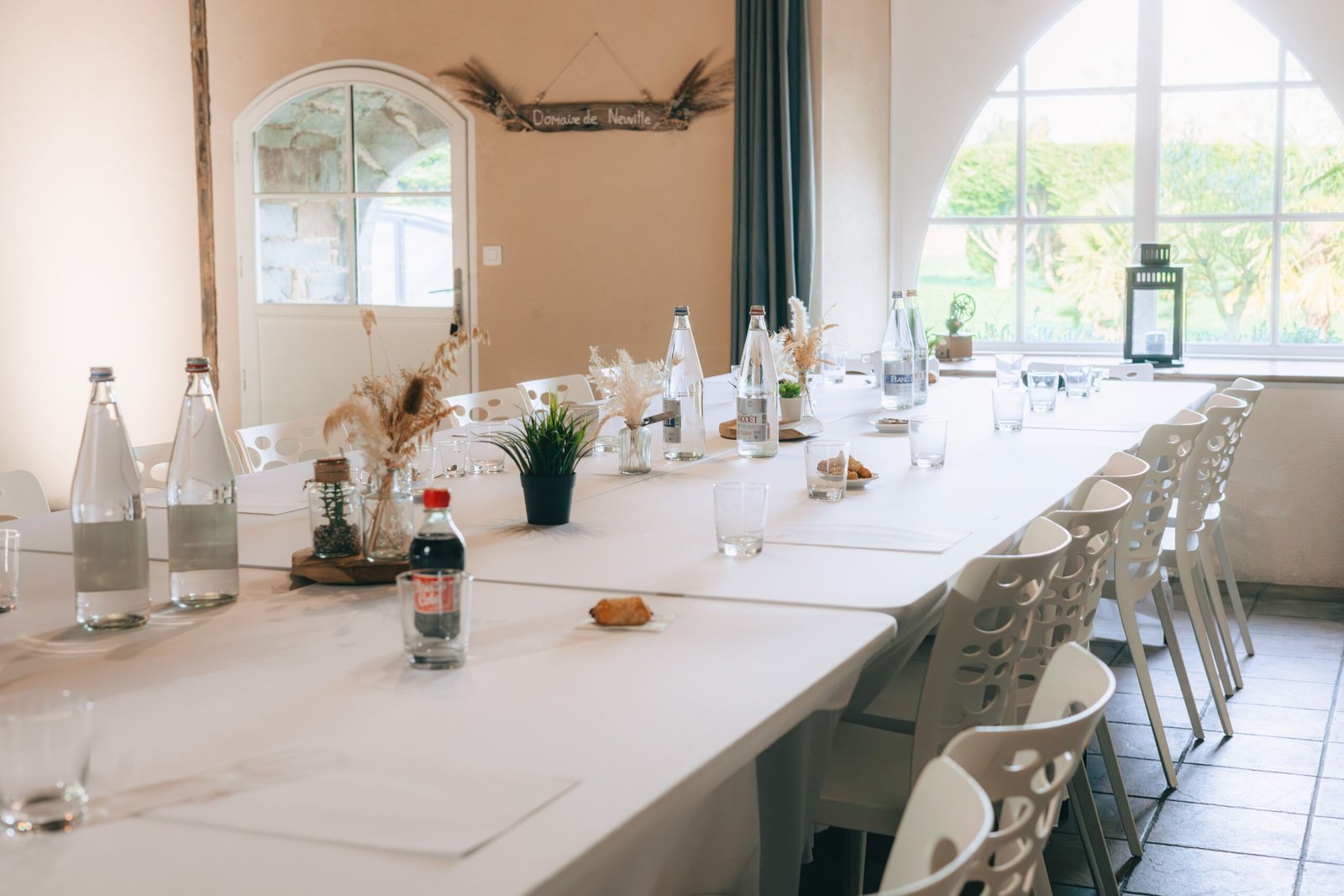 A beautifully set conference room with natural sunlight, water bottles, and minimal decor.