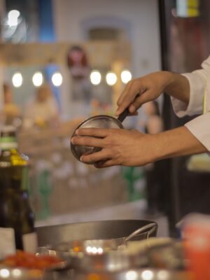 A chef carefully preparing a meal in a warmly lit, cozy restaurant kitchen setting.
